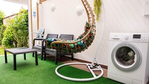 A laundry area with a washing machine, a bench, and a hanging chair. - TOWNHOUSE WITH GARDEN NEAR STATION (Dunkerque)