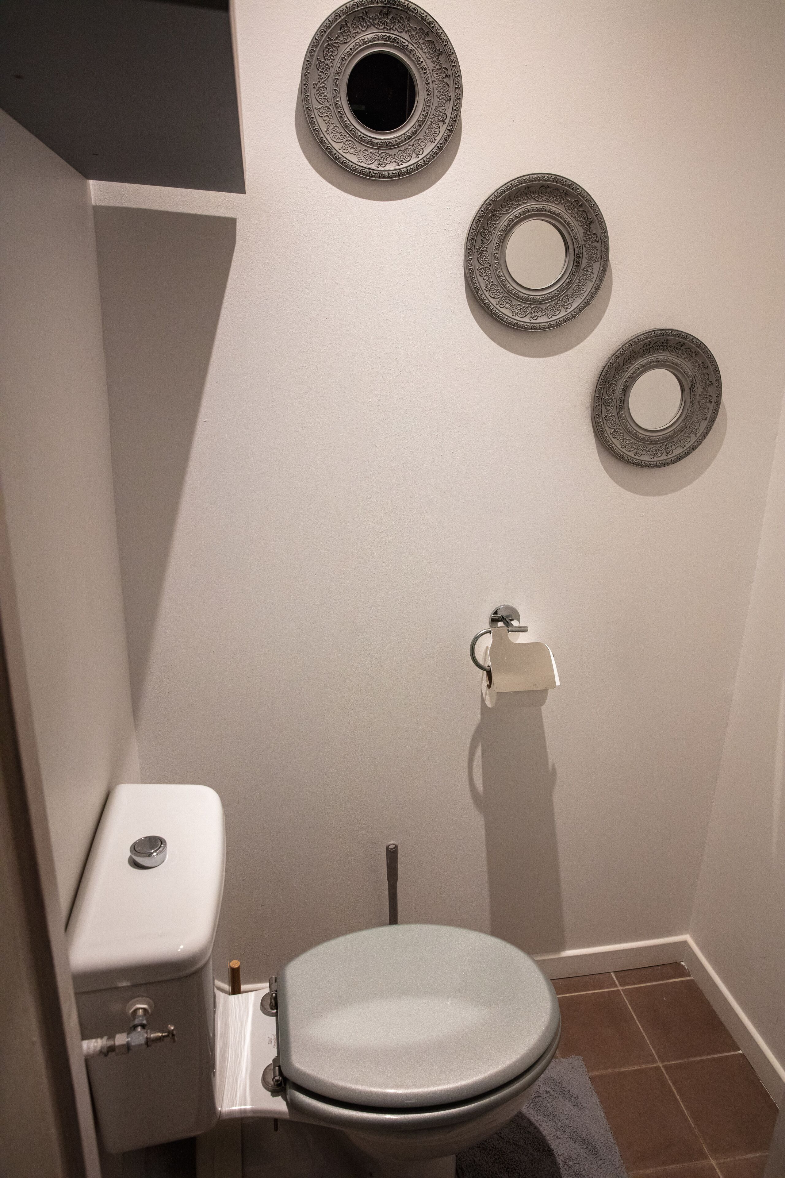 Ein Badezimmer mit Toilette, Handtuchhalter und drei dekorativen Bildern an der Wand.