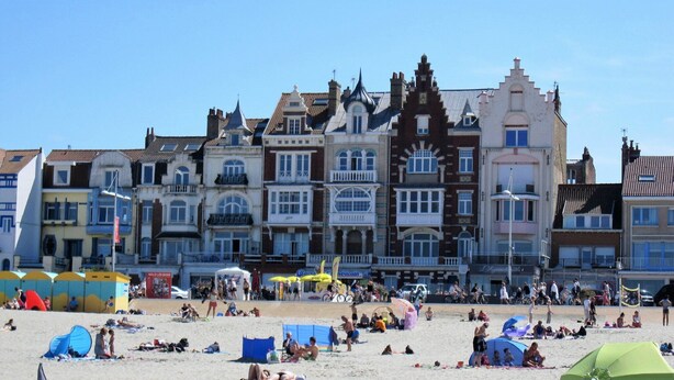 A beach with people sunbathing and swimming, and a row of colorful buildings with balconies. - TOWNHOUSE WITH GARDEN NEAR STATION (Dunkerque)