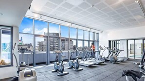 Ein modernes Fitnessstudio mit verschiedenen Cardiogeräten, großen Fenstern und Stadtblick sowie einer großzügigen Gestaltung.