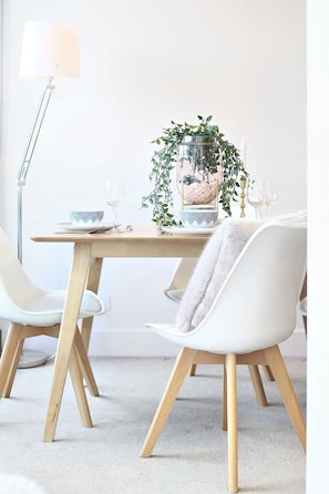 A dining table with a plant centerpiece, white chairs, and a lamp.