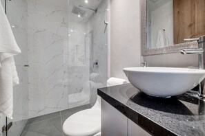 Ein modernes Badezimmer mit einer Duschkabine, einer weißen Toilette und einem großzügigen Waschtisch.