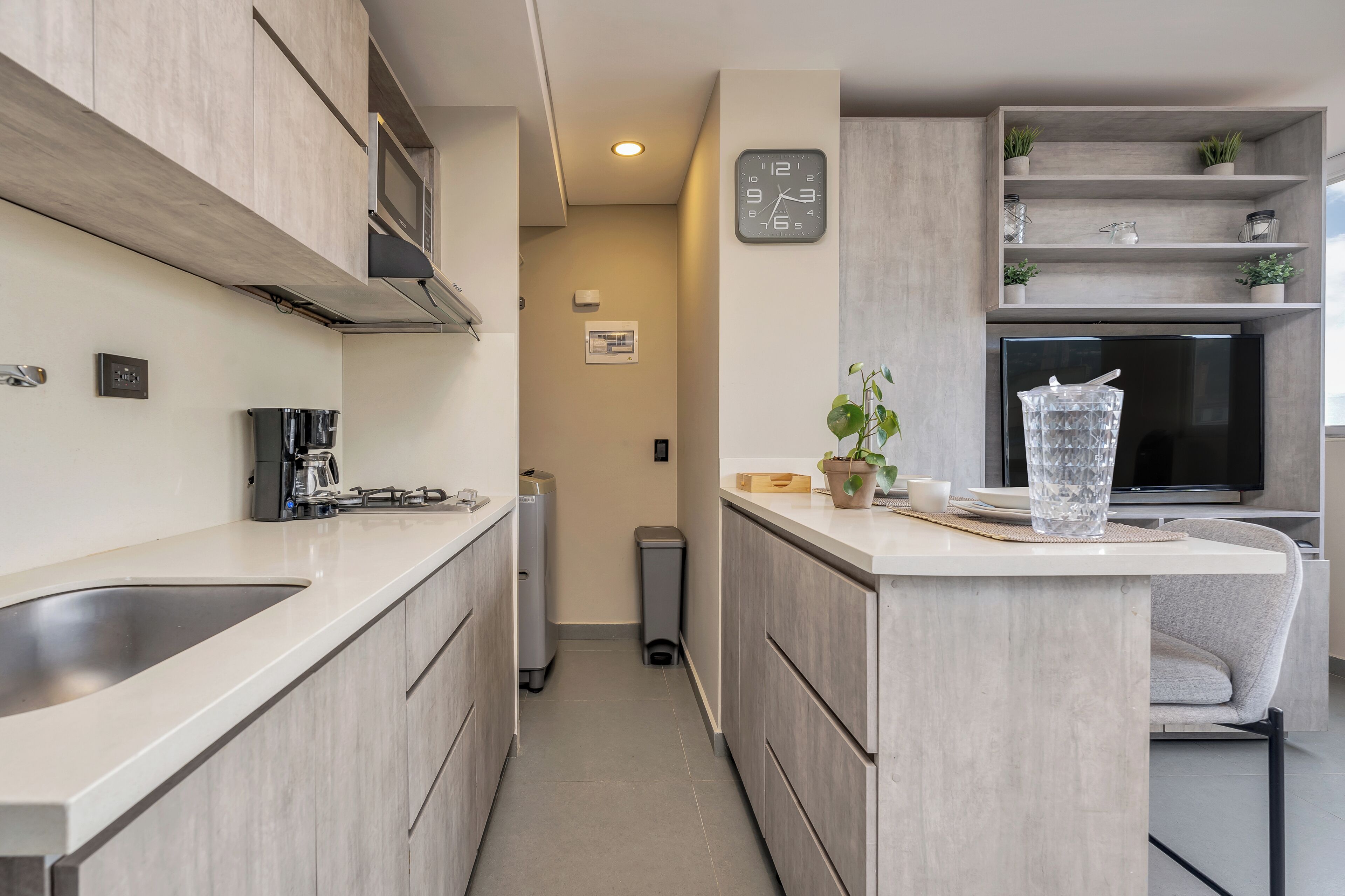 A modern kitchen with a central island, built-in microwave, and a clock on the wall.