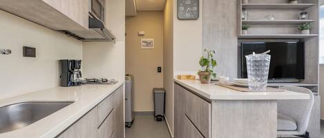 A modern kitchen with a central island, built-in microwave, and a clock on the wall.