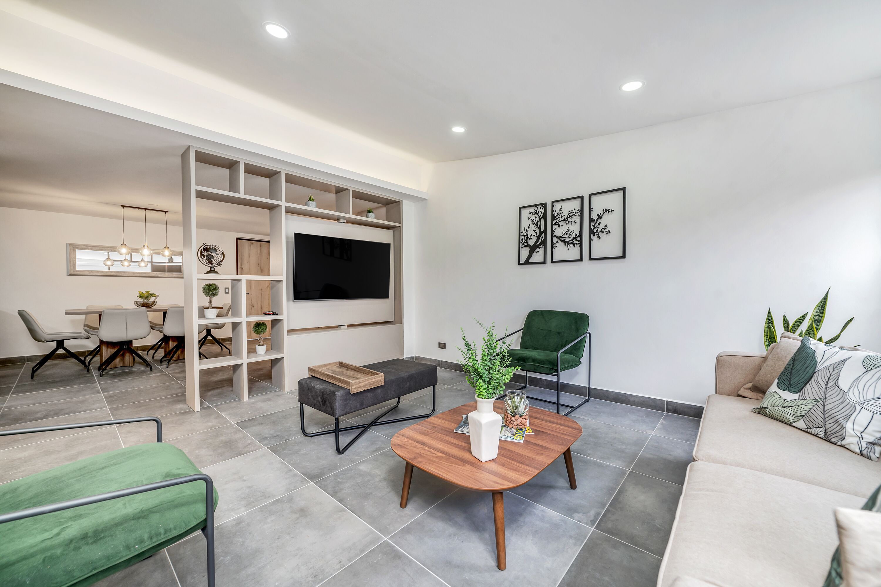 Una sala de estar moderna con un sofá, una mesa de centro, un televisor y un comedor con sillas y una mesa.