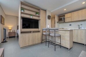 Una cocina moderna con armarios de madera, televisión integrada y dos taburetes de bar.