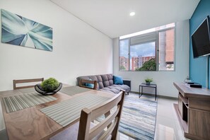 Ein modernes Wohnzimmer mit Esstisch, Sofa und Fernseher.