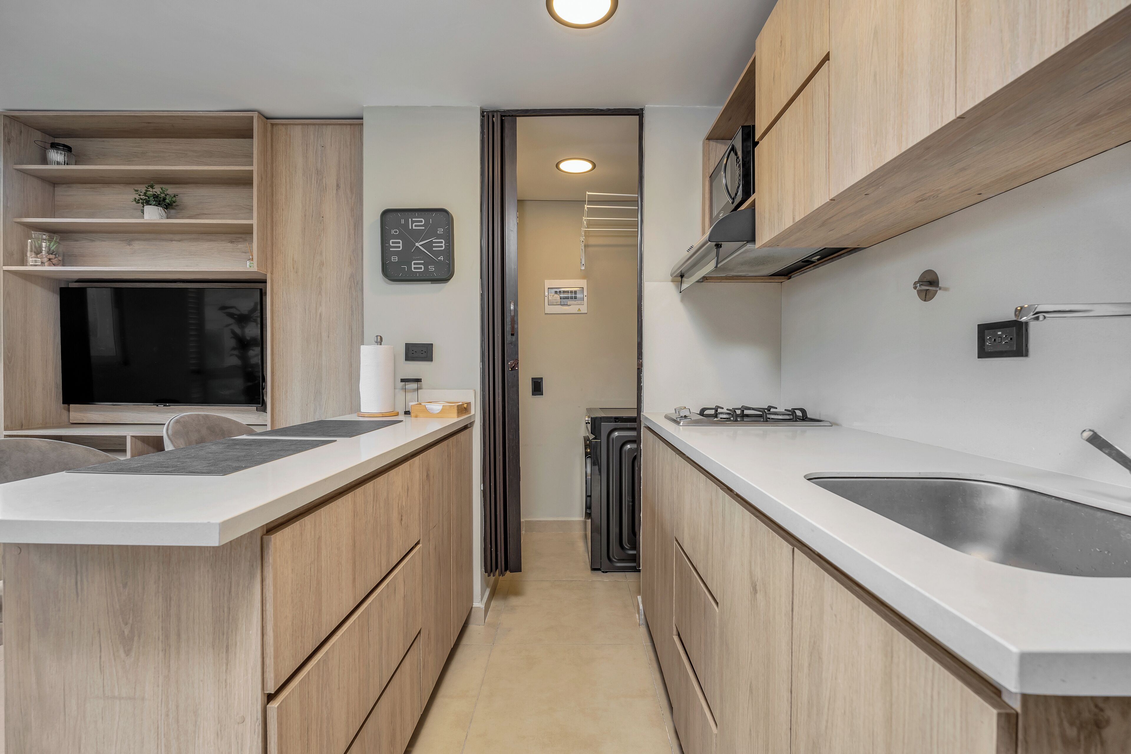 A modern kitchen with wooden cabinets, a built-in oven, and a large window.