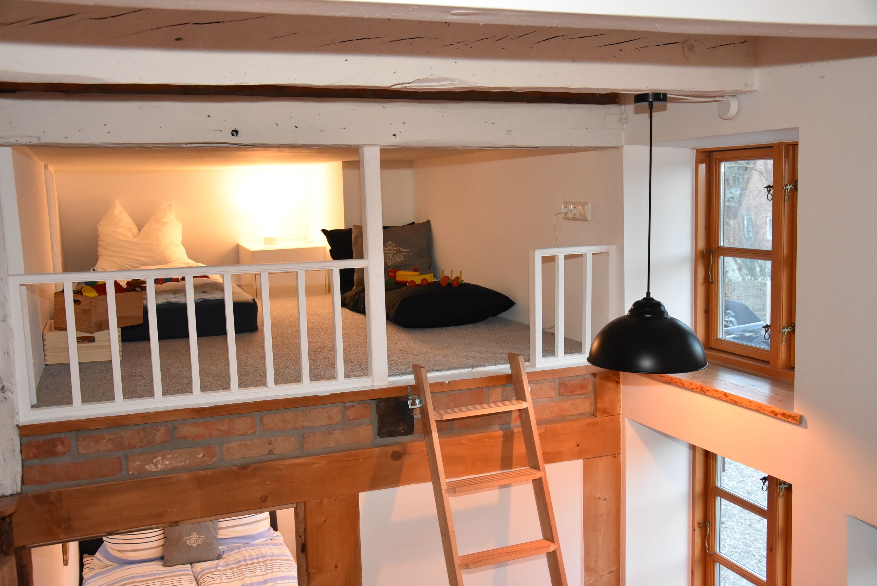 Dormitorio tipo loft con escalera de madera, cuna blanca y ventana con vistas.