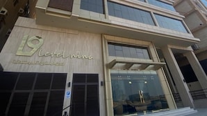 Un edificio moderno con un llamativo letrero que dice 'Level Nine', cuenta con una entrada de vidrio y una rampa que conduce a la entrada principal.