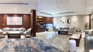 Un hall amplio con una zona de estar grande, un mostrador de recepción y una barra de café.