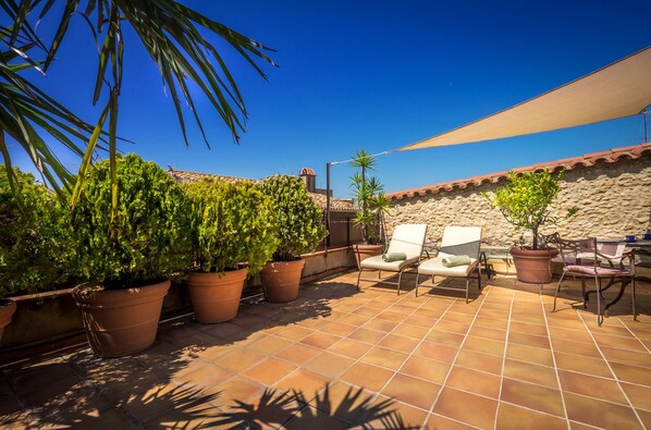 A patio with terracotta tiles, potted plants, and outdoor furniture under a large shade sail. - CAN FELIP Penthouse with Fantastic Views (Palafrugell)