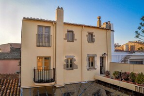A two-story building with a balcony, a chimney, and a small garden area with potted plants. - CAN FELIP Penthouse with Fantastic Views (Palafrugell)