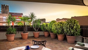 A rooftop terrace with potted plants, a table with chairs, and a view of buildings in the background. - CAN FELIP Penthouse with Fantastic Views (Palafrugell)