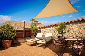 A terrace with two lounge chairs, a table, and chairs, surrounded by potted plants and a stone wall. - CAN FELIP Penthouse with Fantastic Views (Palafrugell)