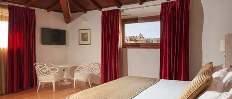 A hotel room with a bed, a desk, chairs, and a window with a city view.
