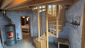 Una habitación con estufa de leña, una escalera en espiral y una cama con ropa de cama estampada.