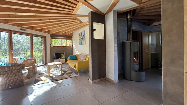 Un interior moderno con techo de madera, un sofá, un televisor y una zona de cocina.