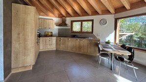 Una cocina moderna con armarios de madera, una mesa de comedor con sillas y un ventanal grande.