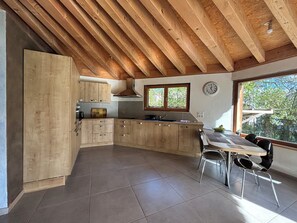 Eine moderne Küche mit Holzausstattung, einem Esstisch mit Stühlen und einem großen Fenster.