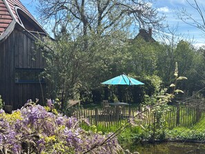 Ein hölzernes Gebäude, ein Holzzaun und ein Teich mit violetten Blumen.