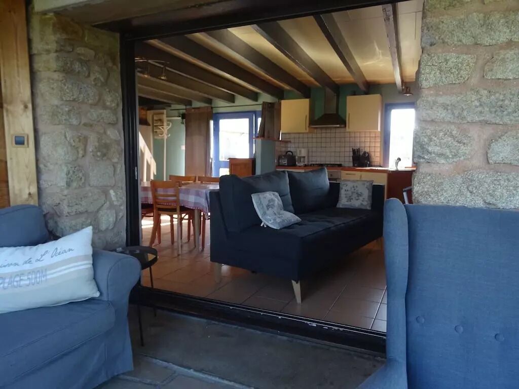 Una sala de estar acogedora, con un sofá y un rincón de comedor a la vista a través de un vidrio.