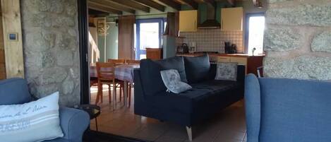 Una sala de estar acogedora, con un sofá y un rincón de comedor a la vista a través de un vidrio.