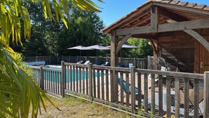 Eine Holzterrasse mit Pool, Liegestühlen und Sonnenschirmen.