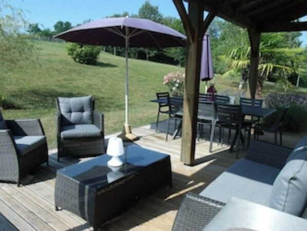 Relax on the patio surrounded by lush greenery and enjoy a meal at the dining table.