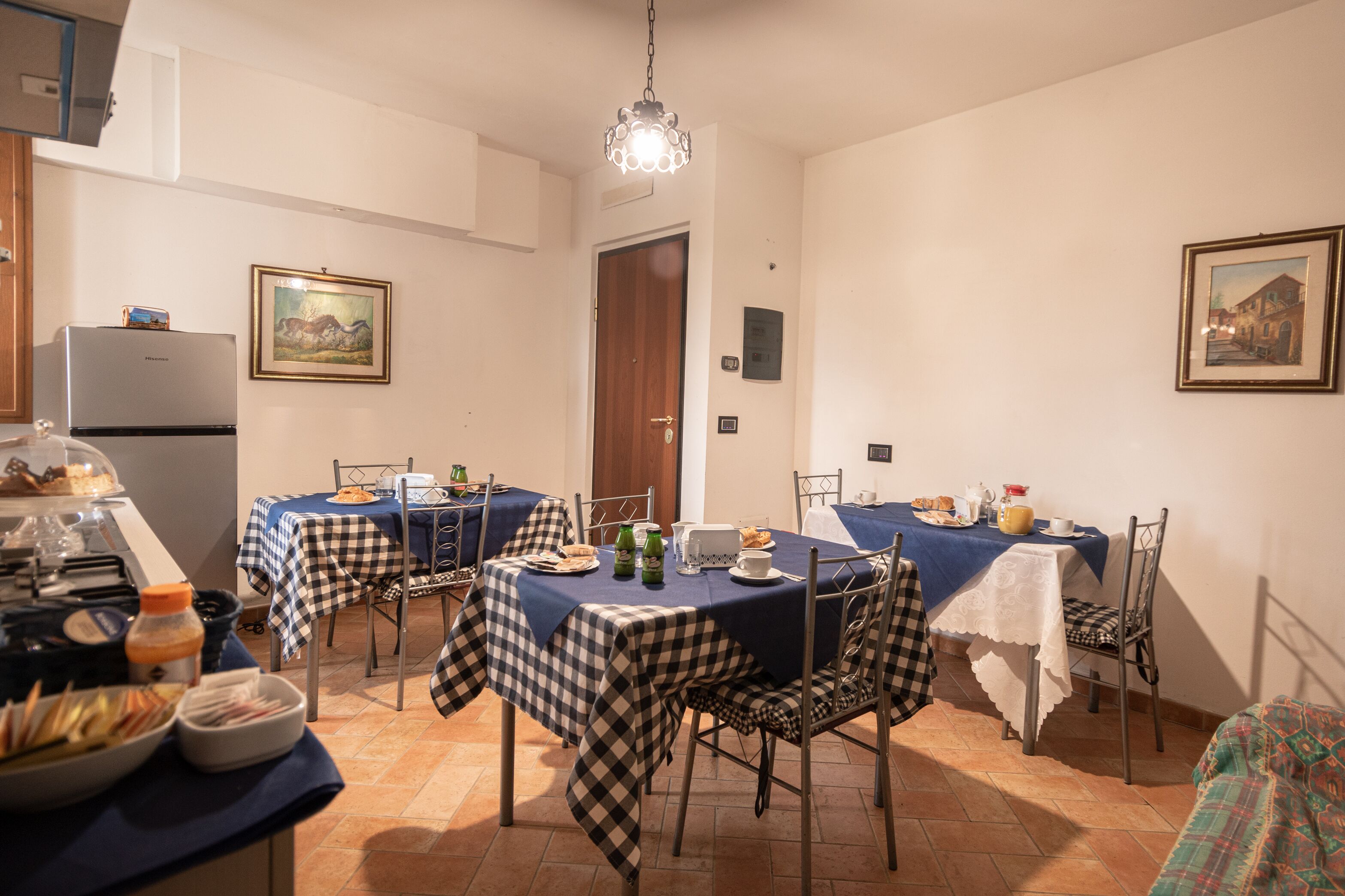 A dining area with checkered tablecloths, metal chairs, and a chandelier.