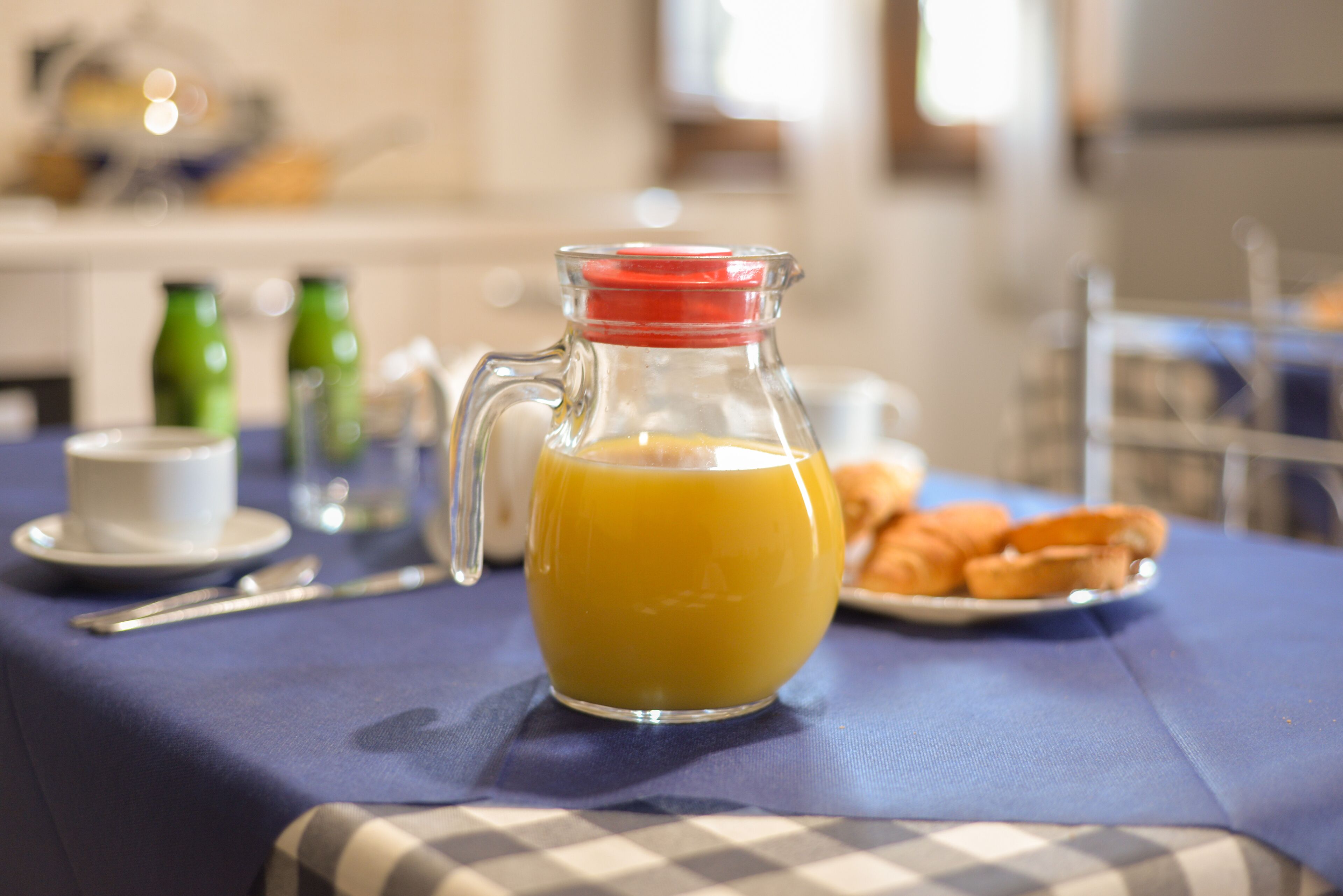 Et morgenbord med en kande appelsinjuice, en kop og et fad med kager.
