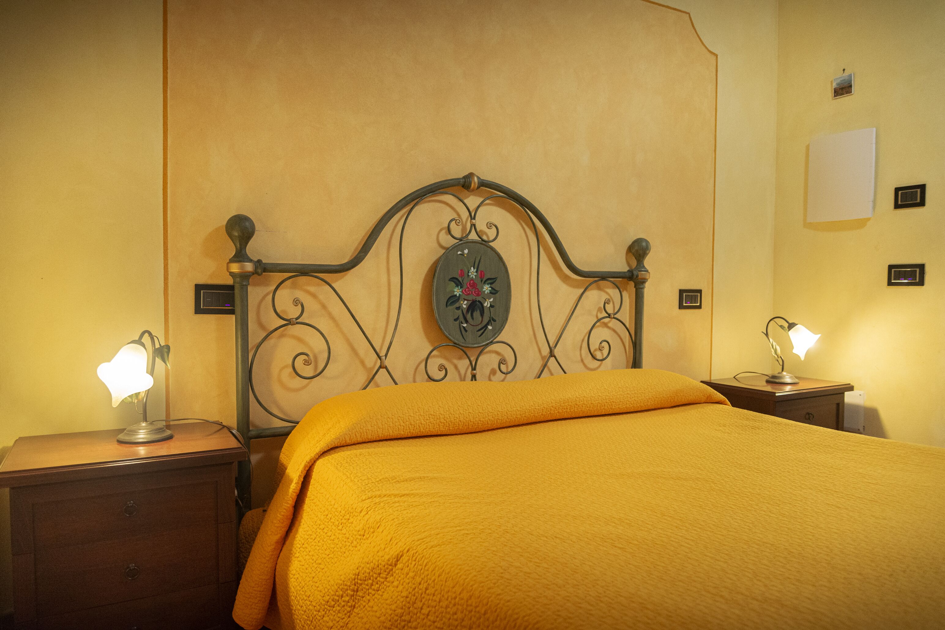 A neatly made bed with a headboard, two bedside tables with lamps, and a wall-mounted clock.