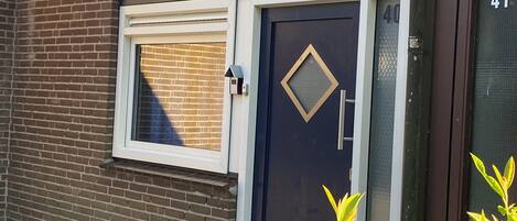 Eine dunkle Tür mit Fenster darüber, eine Ziegelwand und die Zahl 41 auf der rechten Seite.