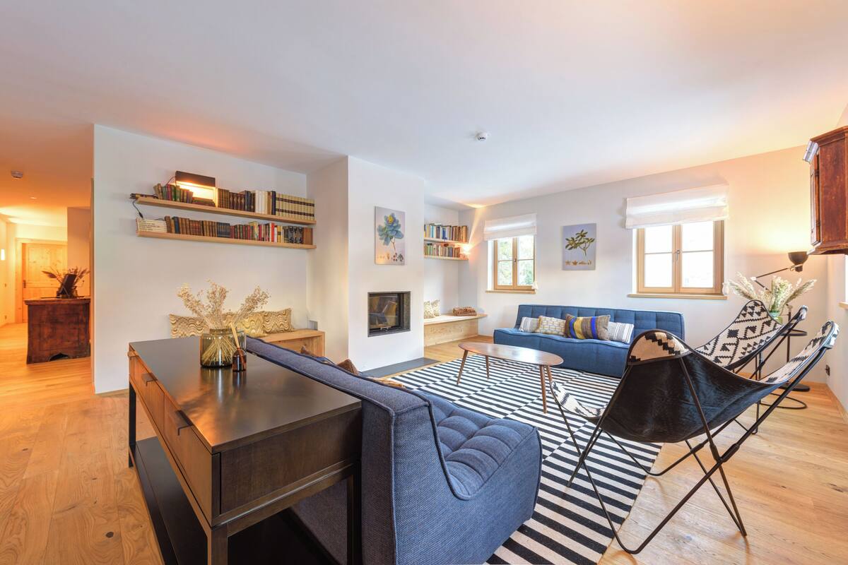 Un salon moderne avec un canapé bleu, un tapis noir et blanc et une bibliothèque.
