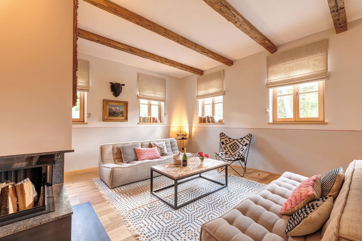 Un salon chaleureux avec une cheminée, un canapé, une table basse et un tapis à motifs.