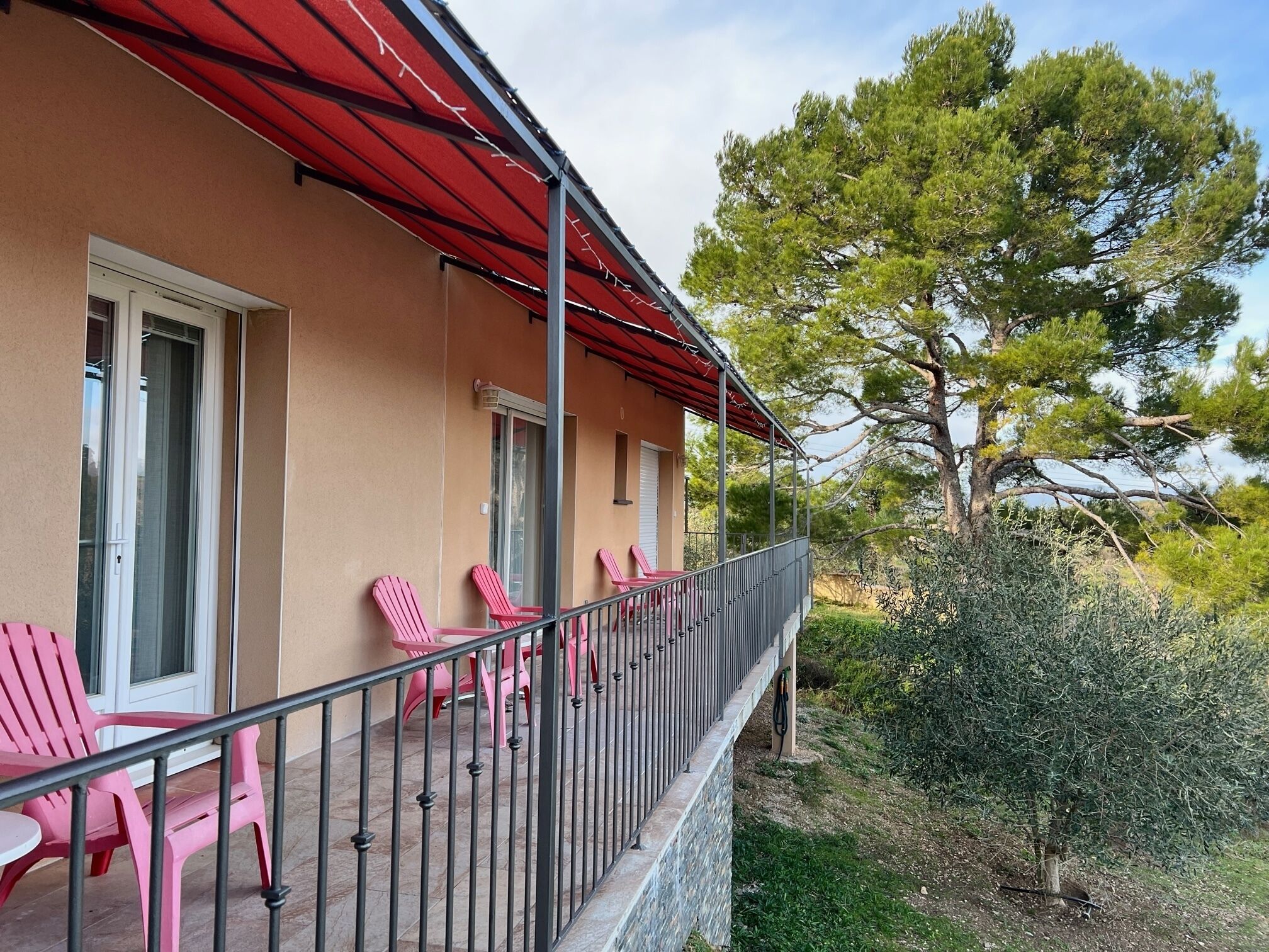 Un balcon avec des chaises roses et un auvent rouge.
