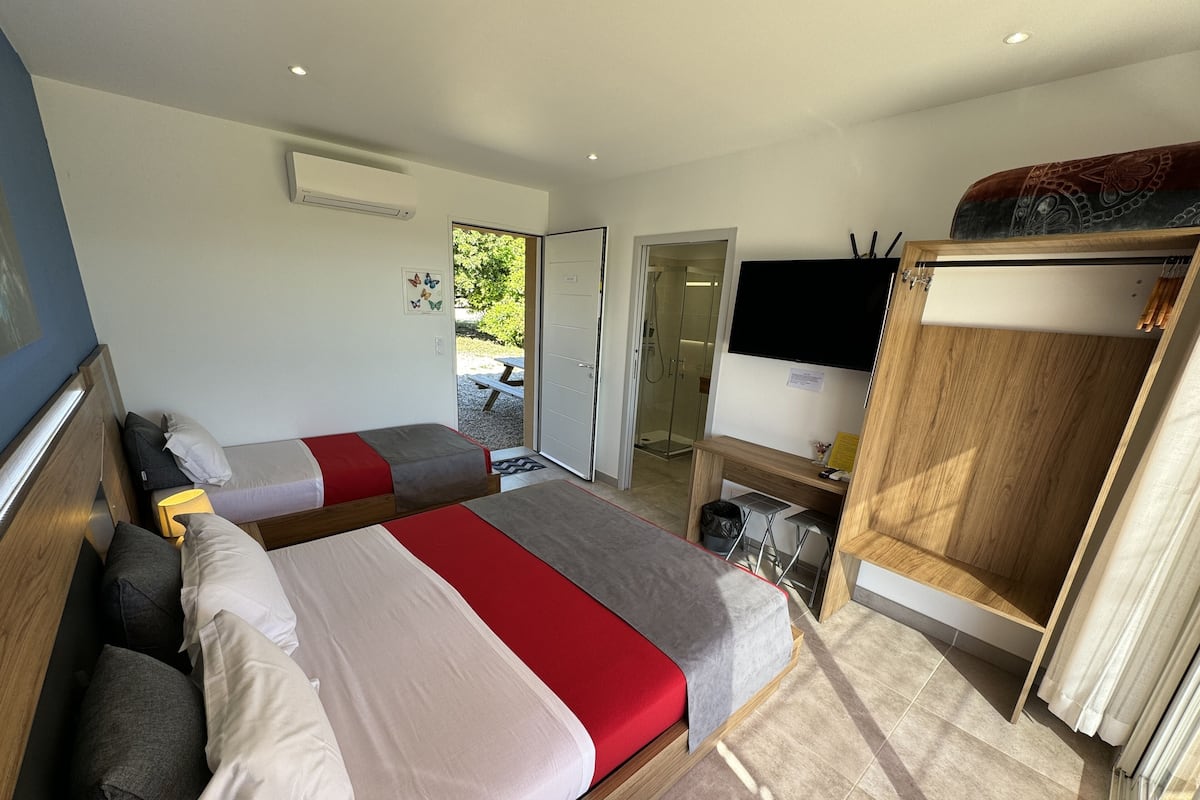 Een hotelkamer met twee bedden, een televisie, een kledingkast en een badkamer zichtbaar door een open deur.