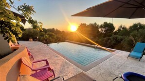 Un espace piscine avec des chaises longues et un parasol.