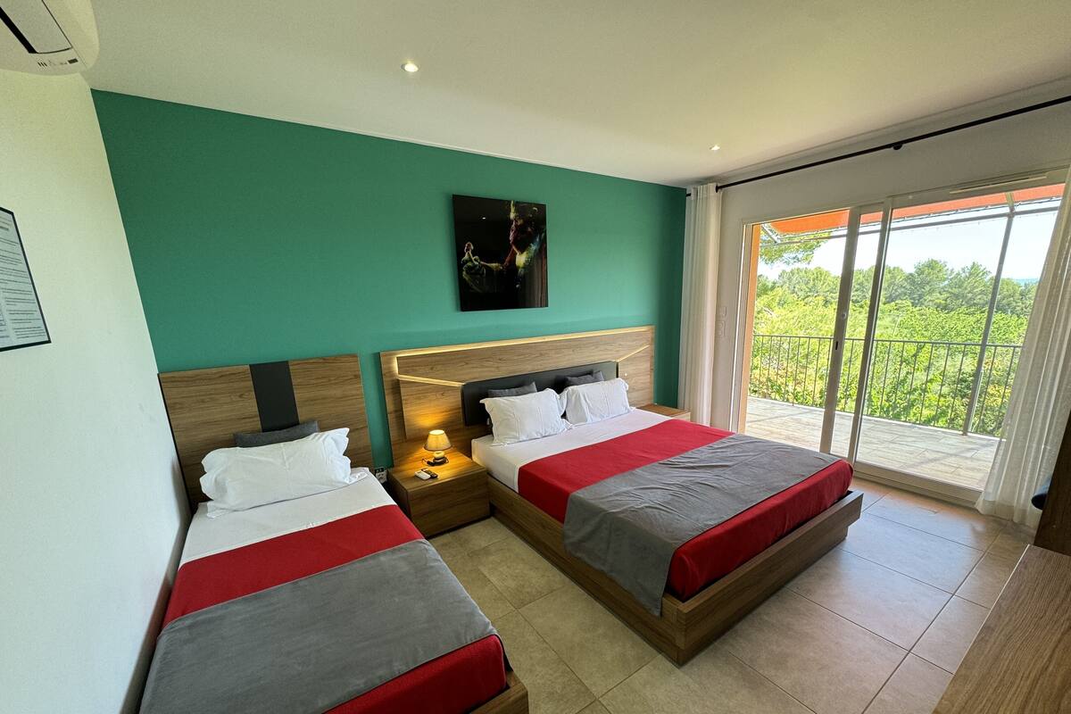 Een hotelkamer met twee bedden, een balkon met uitzicht en een schilderij aan de muur.