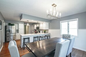 Una cucina moderna con isola centrale, elettrodomestici in acciaio inossidabile e un lampadario.