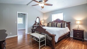 A bedroom with a wooden bed, a bench, a nightstand, a ceiling fan, and a window. - Country  Clean  Cozy (Elizabethtown)