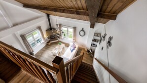 Amplio espacio tipo loft con techo alto, vigas de madera, una escalera, zona de comedor y vistas al exterior.