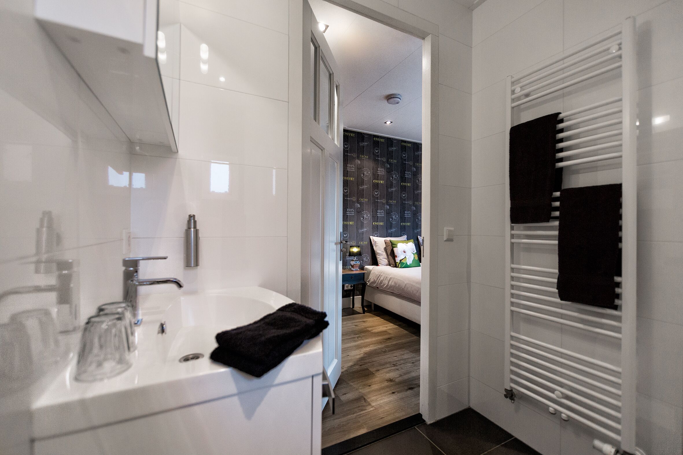A modern bathroom with a white sink, glass, and a black towel.