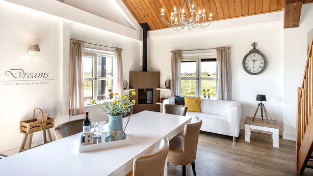 Un salón amplio con una mesa de comedor, sofá y un reloj en la pared.