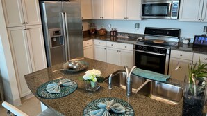 A modern kitchen with white cabinets, stainless steel appliances, and granite countertops.