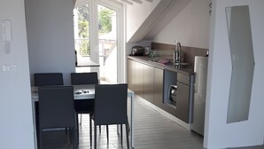 A modern kitchen with a dining area, a glass table with a decorative bowl, and a view of the outdoors. - Penthouse penthouse by the sea Rovinj, Residenza Federica (Rovigno)