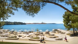 A beachside resort with sun loungers, umbrellas, and a view of the sea. - Penthouse penthouse by the sea Rovinj, Residenza Federica (Rovigno)