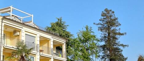 A multi-story building with balconies, surrounded by trees and greenery.