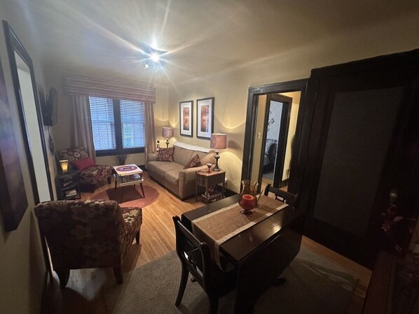 A living room with a dining table, chairs, a sofa, and a TV.