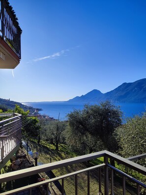 A balcony with a view of a coastal landscape, including mountains and a body of water. - Apartament Malva 2  with balcony and amazing lake view (Brenzone sul Garda)